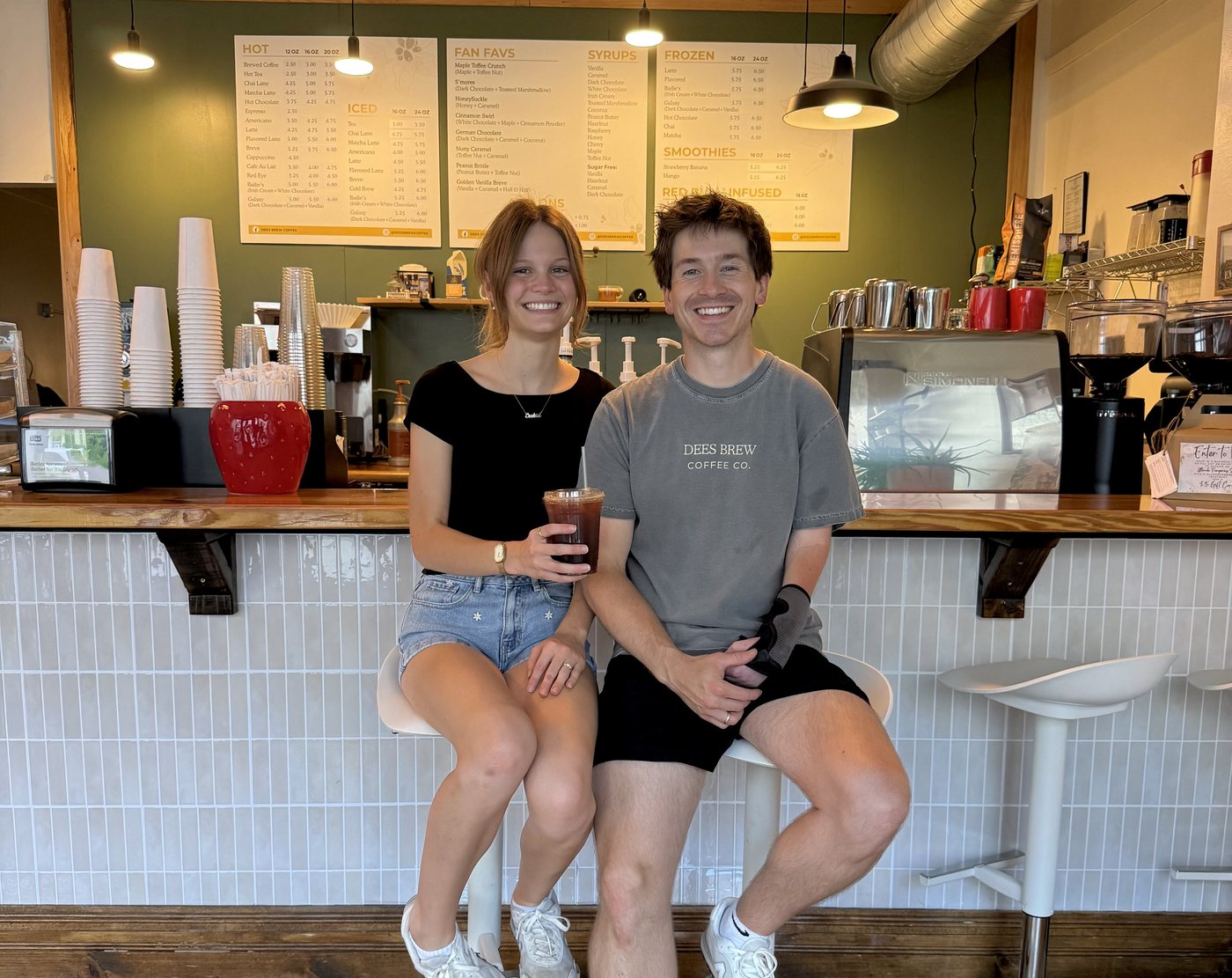 Zeke and Bailie Dees at the counter of Dees Brew Coffee Co., the menu boards on the wall behind them