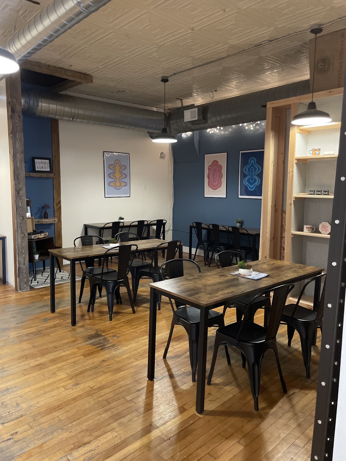 Seating room at Dees Brew Coffee Co., with pressed-tin ceiling, navy walls and long communal tables